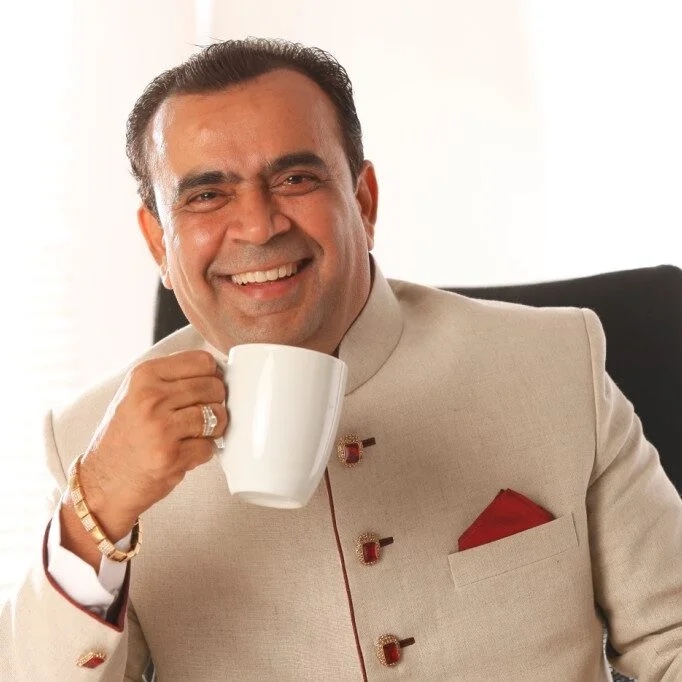 Portrait of Dr. Yogesh Lakhani in a cream bandhgala, holding a cup of tea
