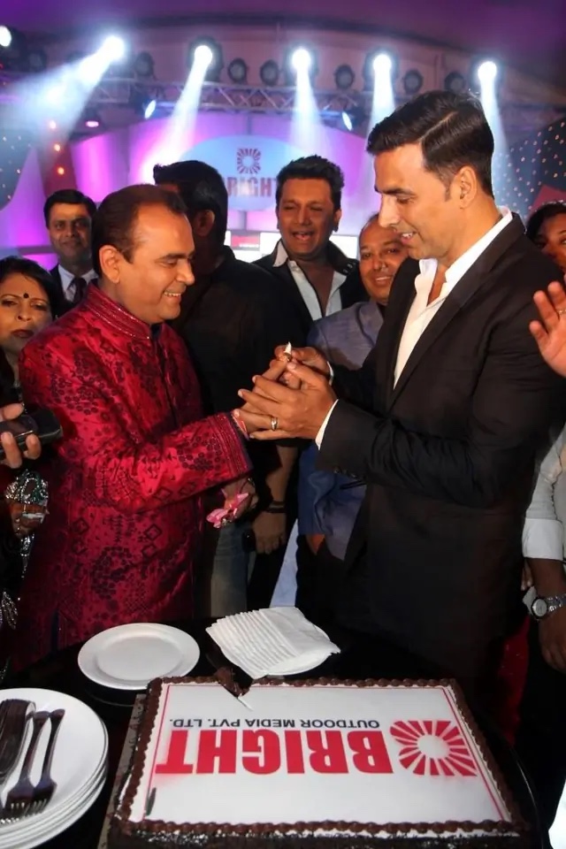 Yogesh Lakhani cutting a Bright Outdoor Media cake with Akshay Kumar at a company celebration