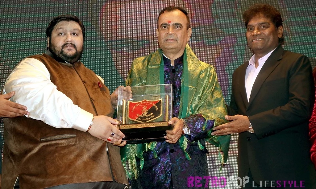 Yogesh Lakhani being felicitated on stage, receiving a memento alongside Johny Lever